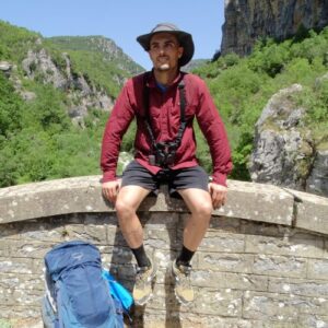 Líder de viagem António Cotão sentado numa ponte na Grécia.